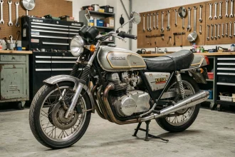 Suzuki GT750 d'occasion garée dans un garage privé, vue 3/4 avant révélant la patine authentique du moteur deux-temps refroidi par eau